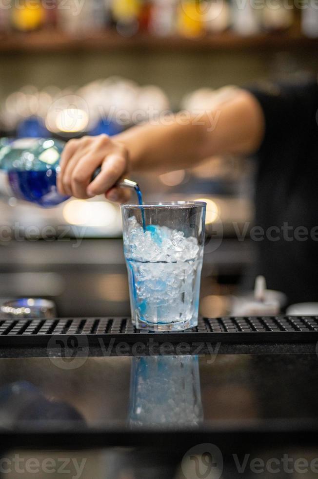 Mano de mujer vertiendo licor en un vaso. foto