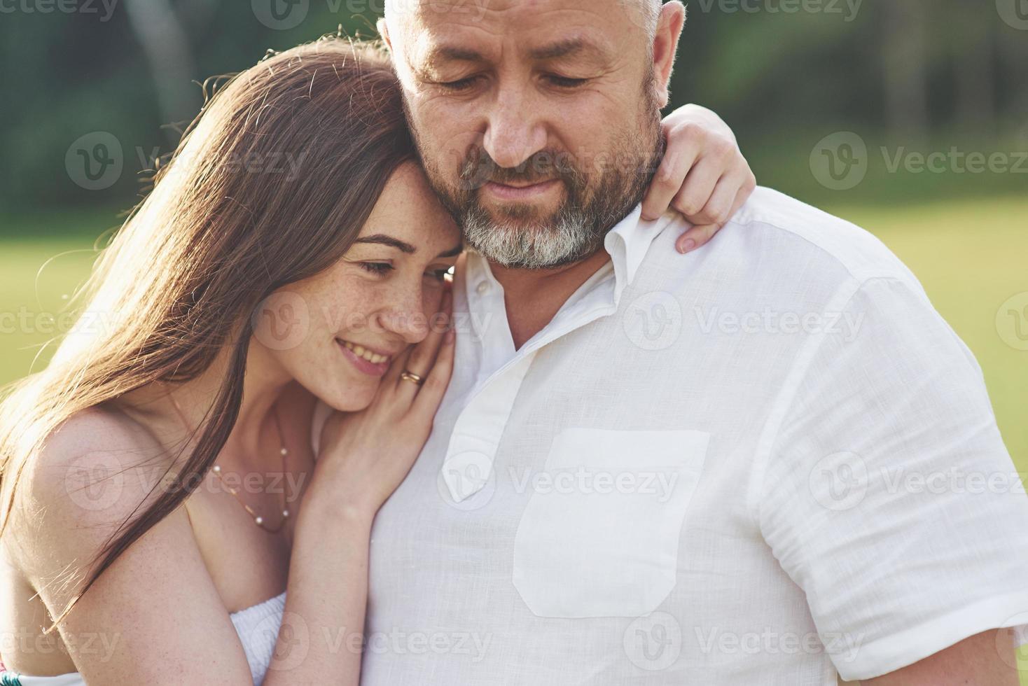 Handsome old man and beautiful young girl are hugging, daughter and her old dad spend time together outdoors photo