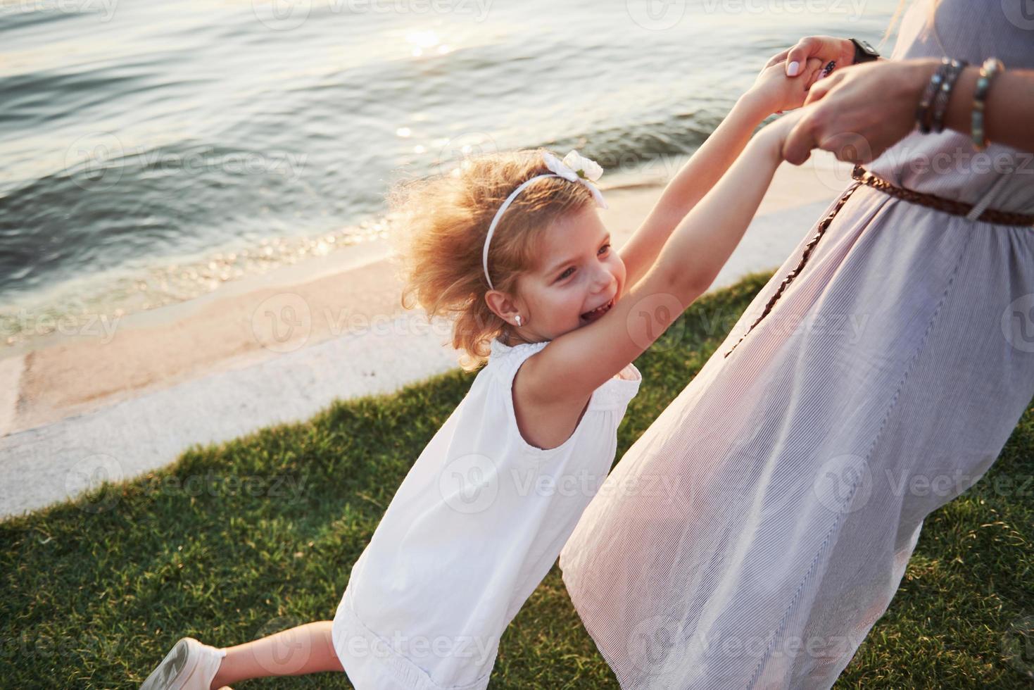 Mom and her little daughter play on the grass near the lake. photo