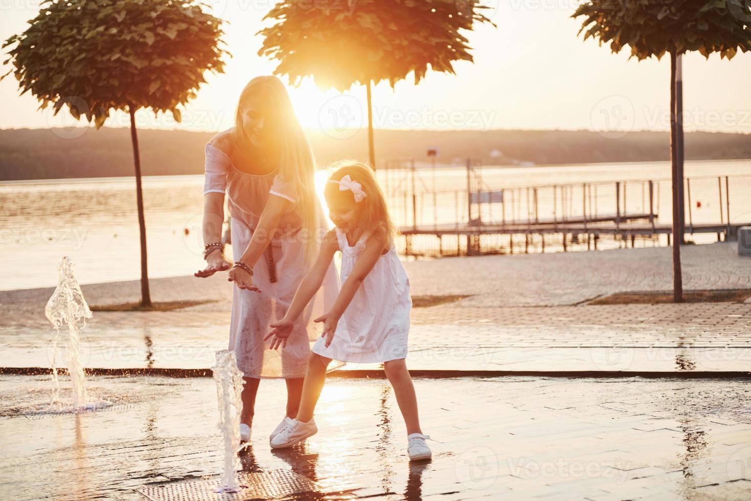 una mujer jugando con un niño cerca del océano en el parque al atardecer foto