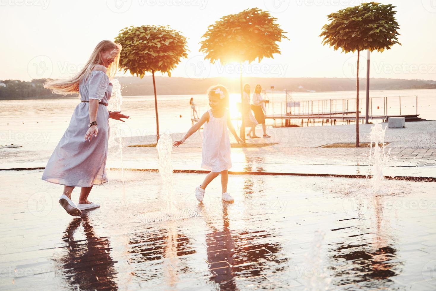 una mujer jugando con un niño cerca del océano en el parque al atardecer foto