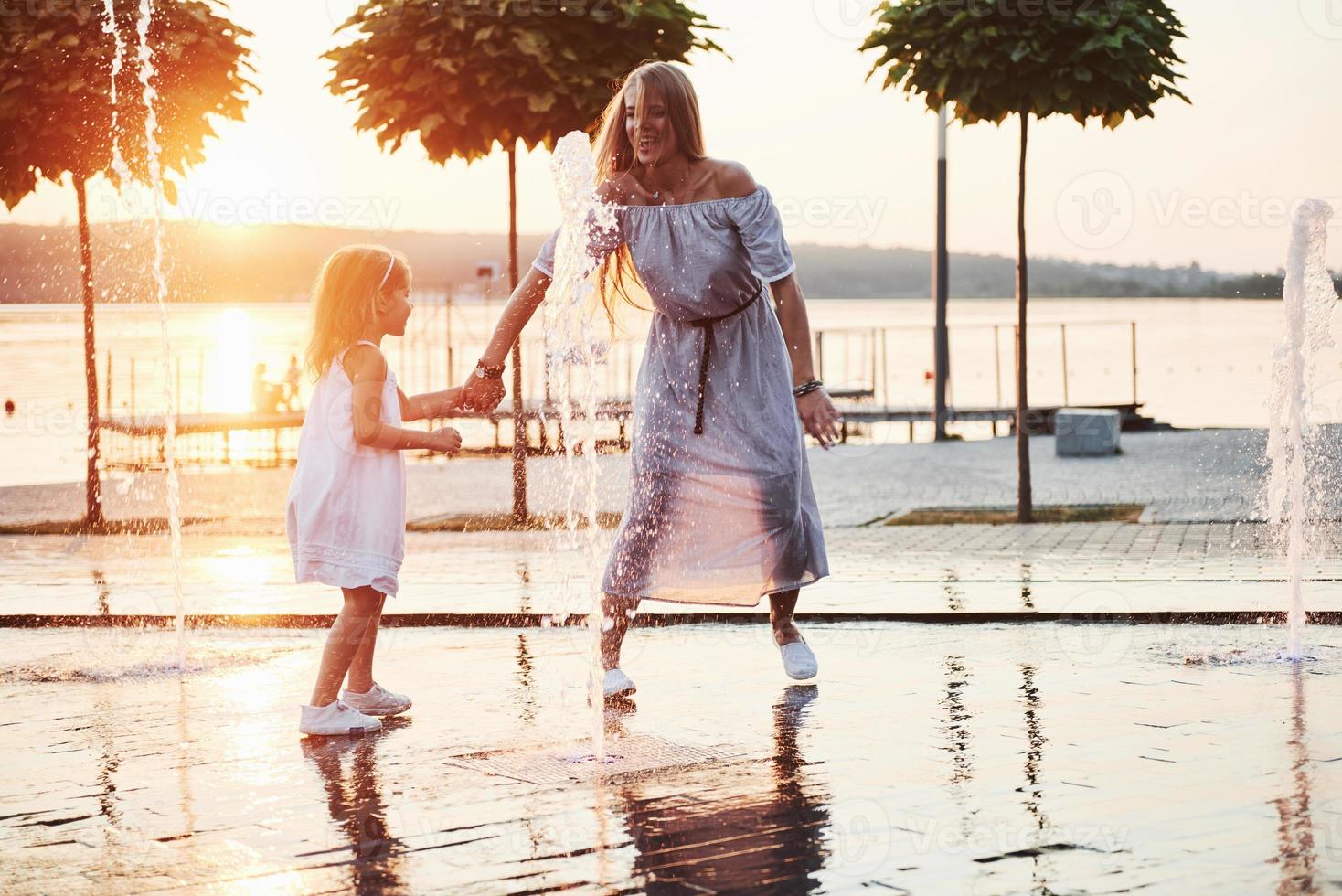 madre con bebé cerca de la fuente al atardecer foto