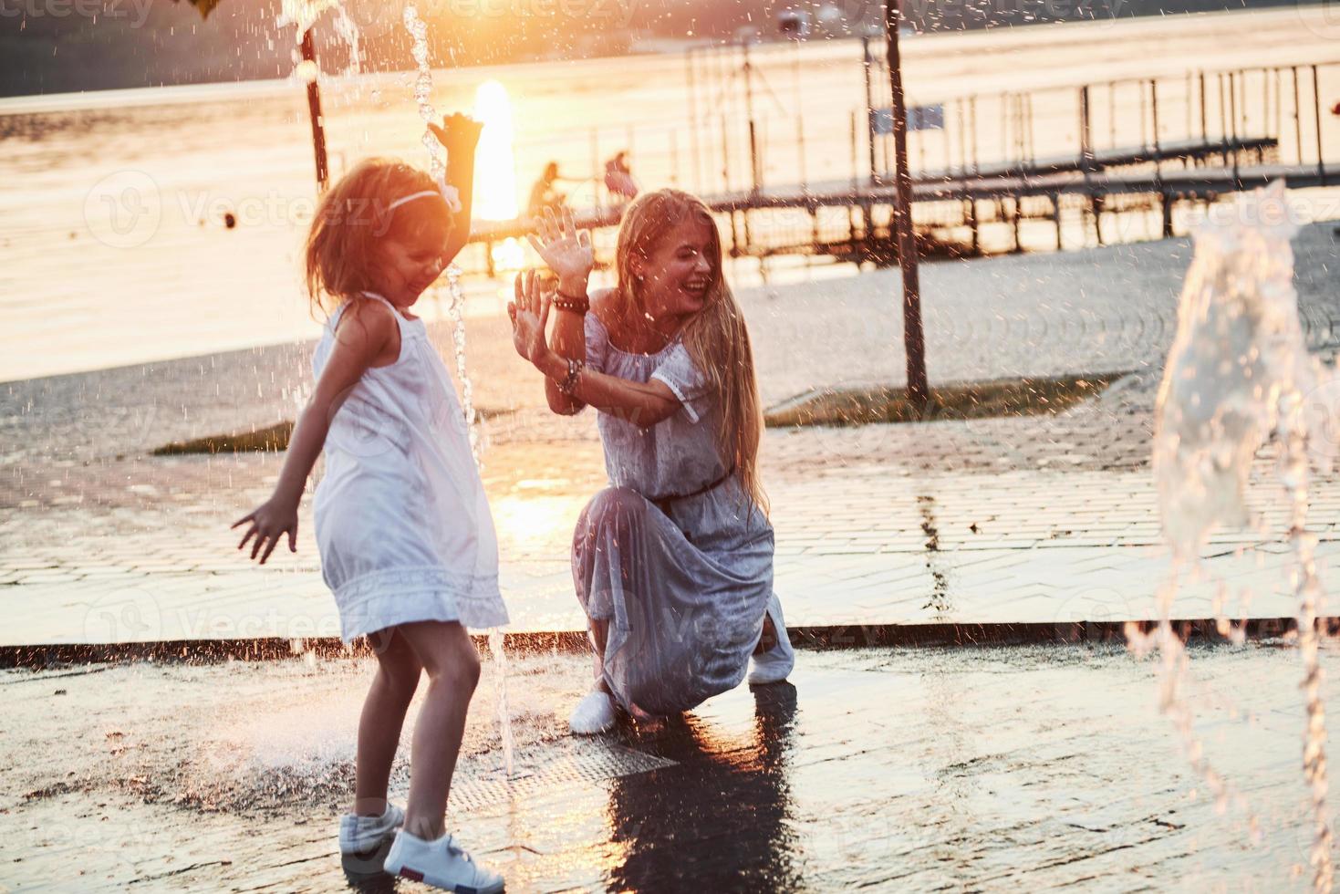 madre con bebé cerca de la fuente al atardecer foto