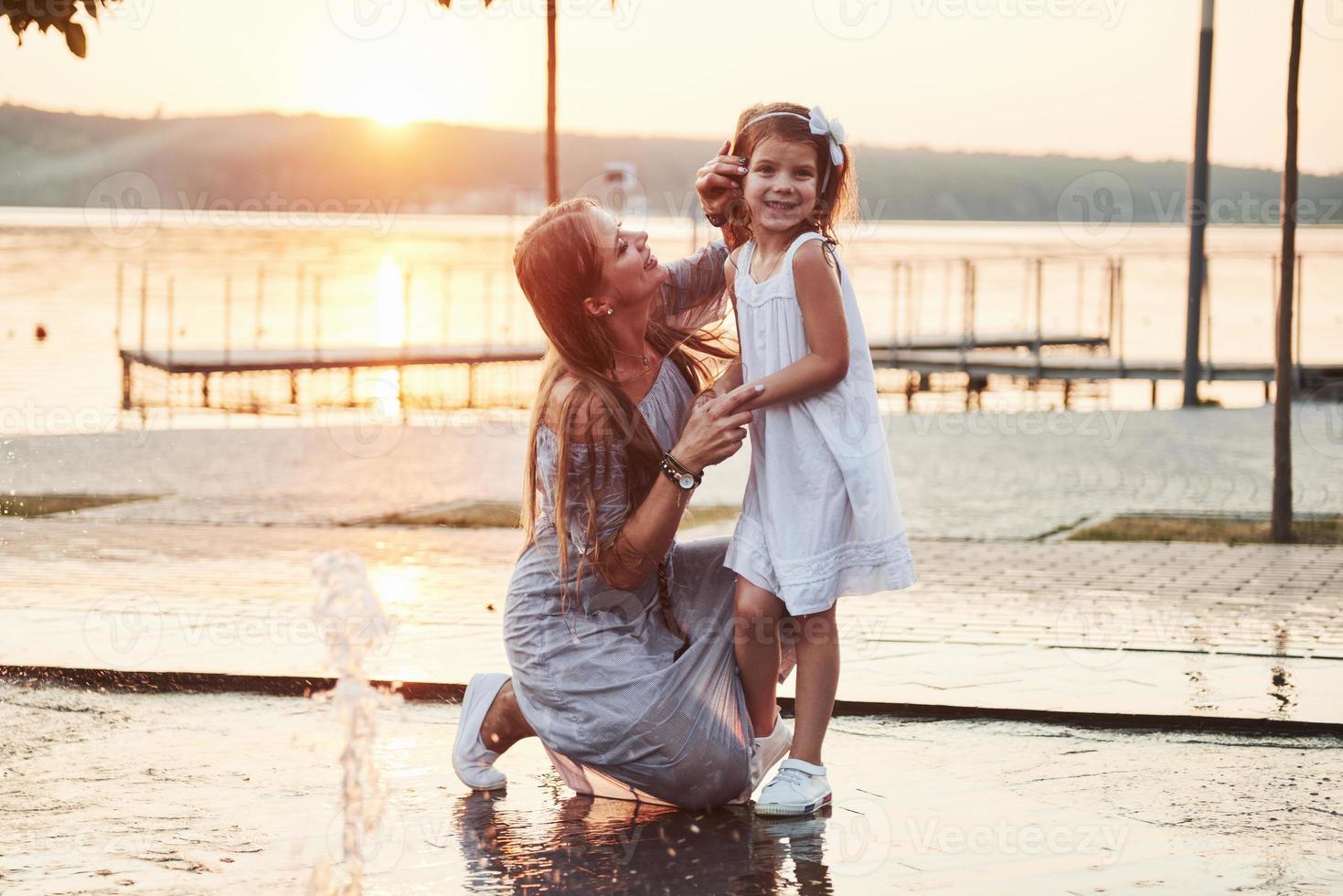 una mujer jugando con un niño cerca del océano en el parque al atardecer foto