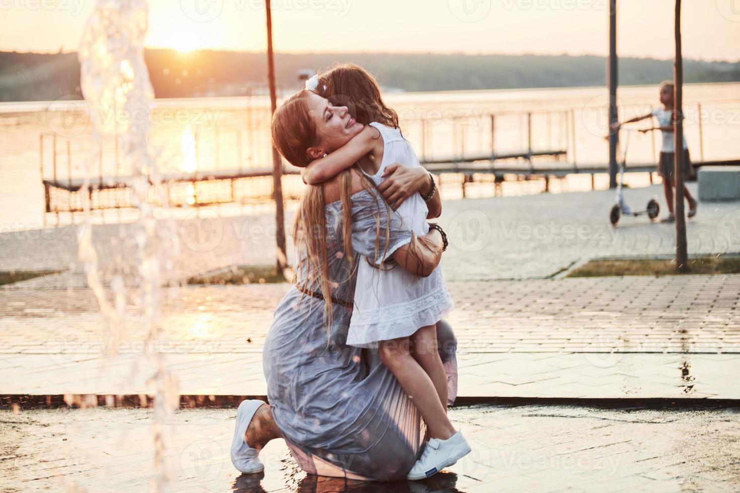 madre con bebé cerca de la fuente al atardecer foto