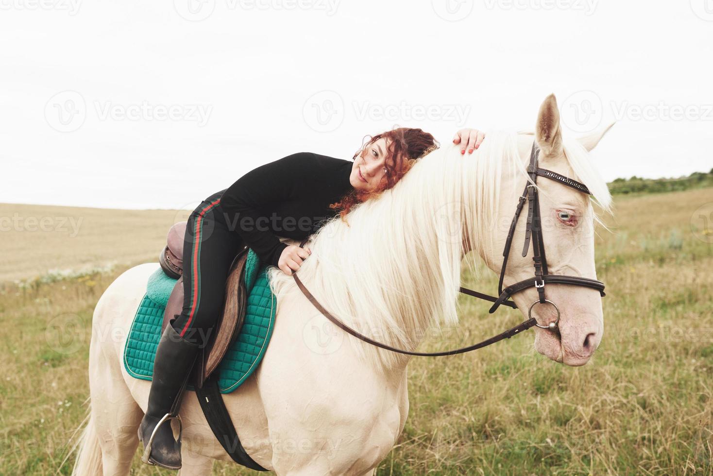 Linda jovencita abrazando a su caballo mientras está sentado a horcajadas. A ella le gustan los animales foto