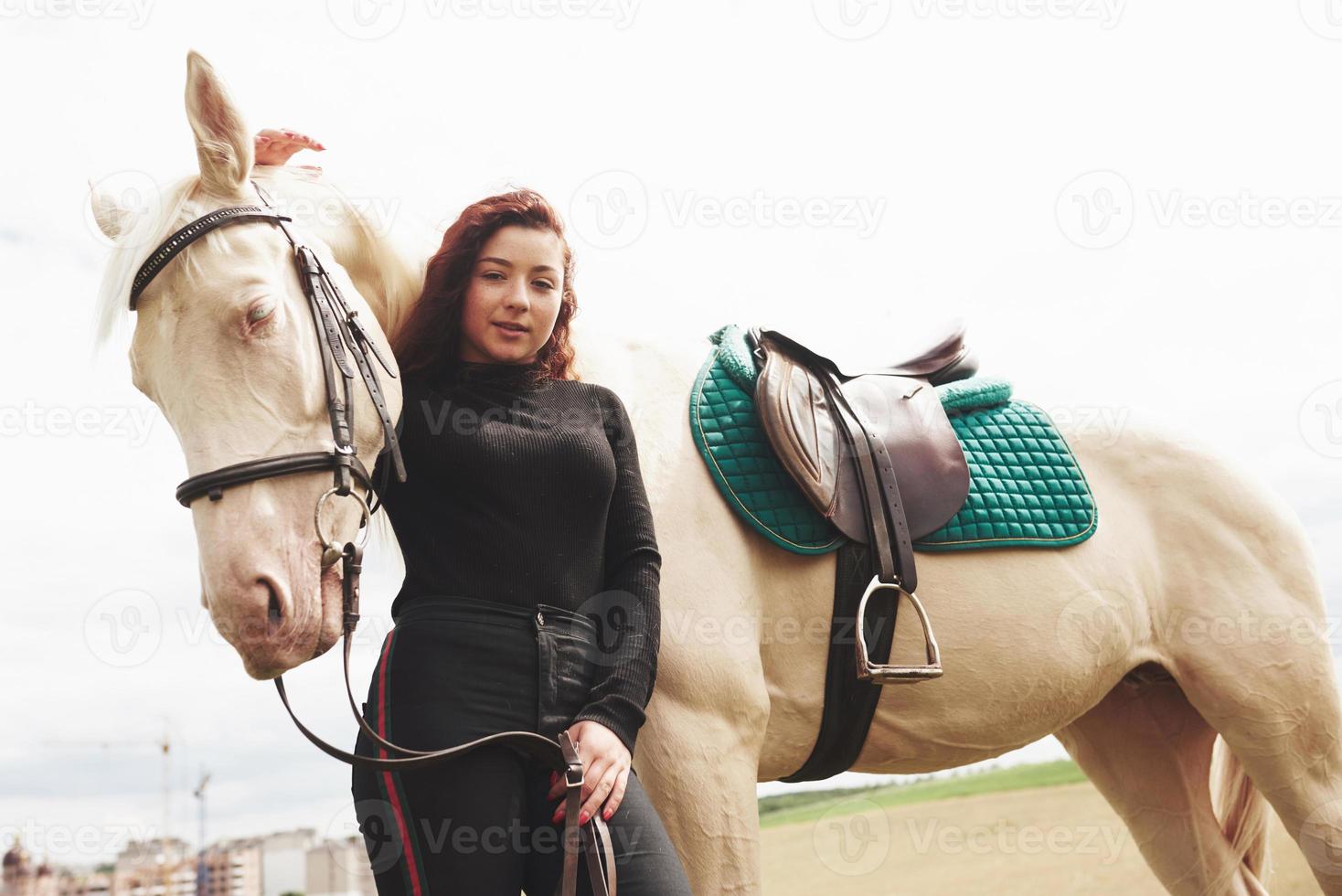 A happy girl communicates with her favorite horse. The girl loves animals andhorseback riding photo