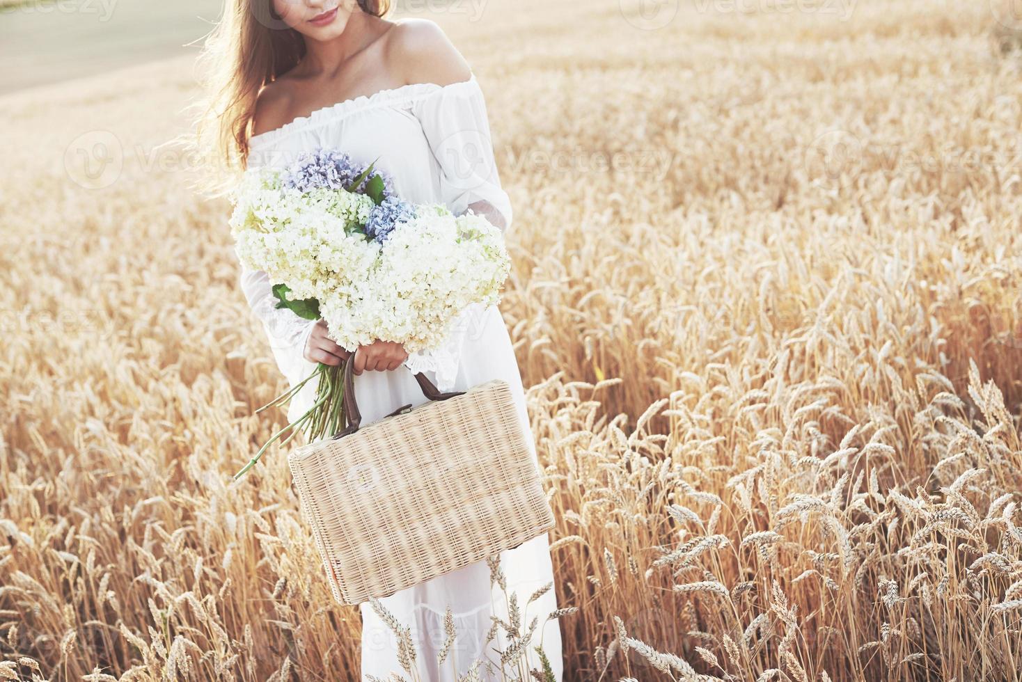 Young sensitive girl in white dress posing in a field of golden wheat photo