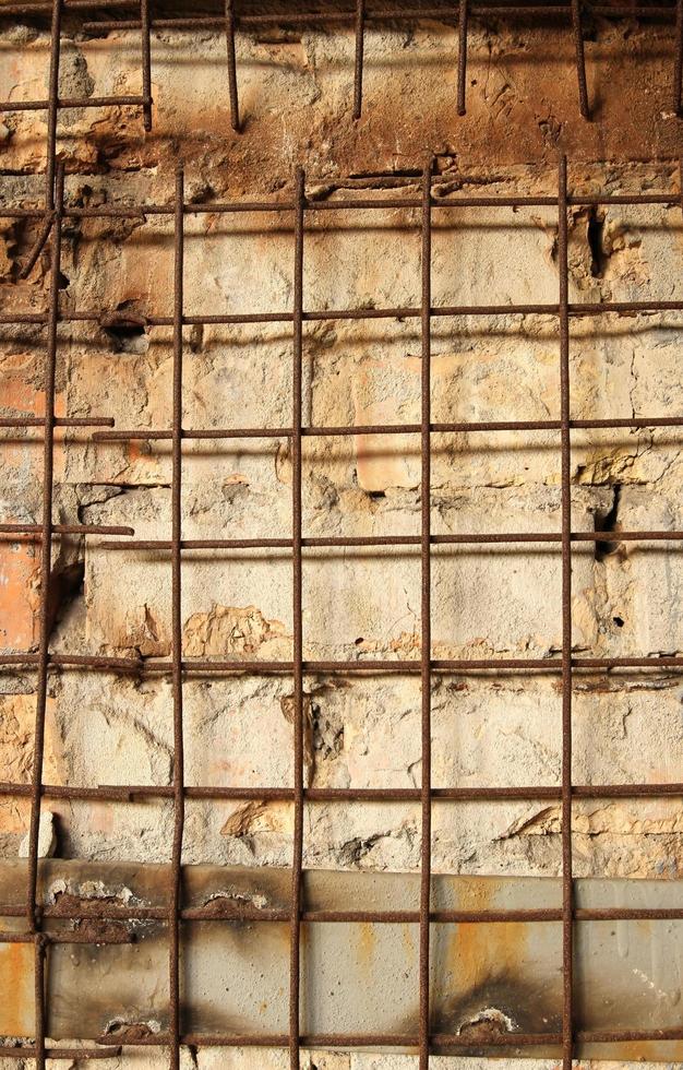 Rusty skeleton lattice of iron rods on a brick wall photo