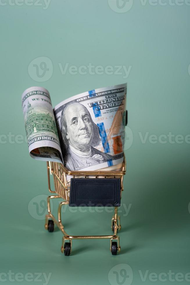 American banknotes dollars in a shopping cart on a light green background. Shopping, discounts. photo