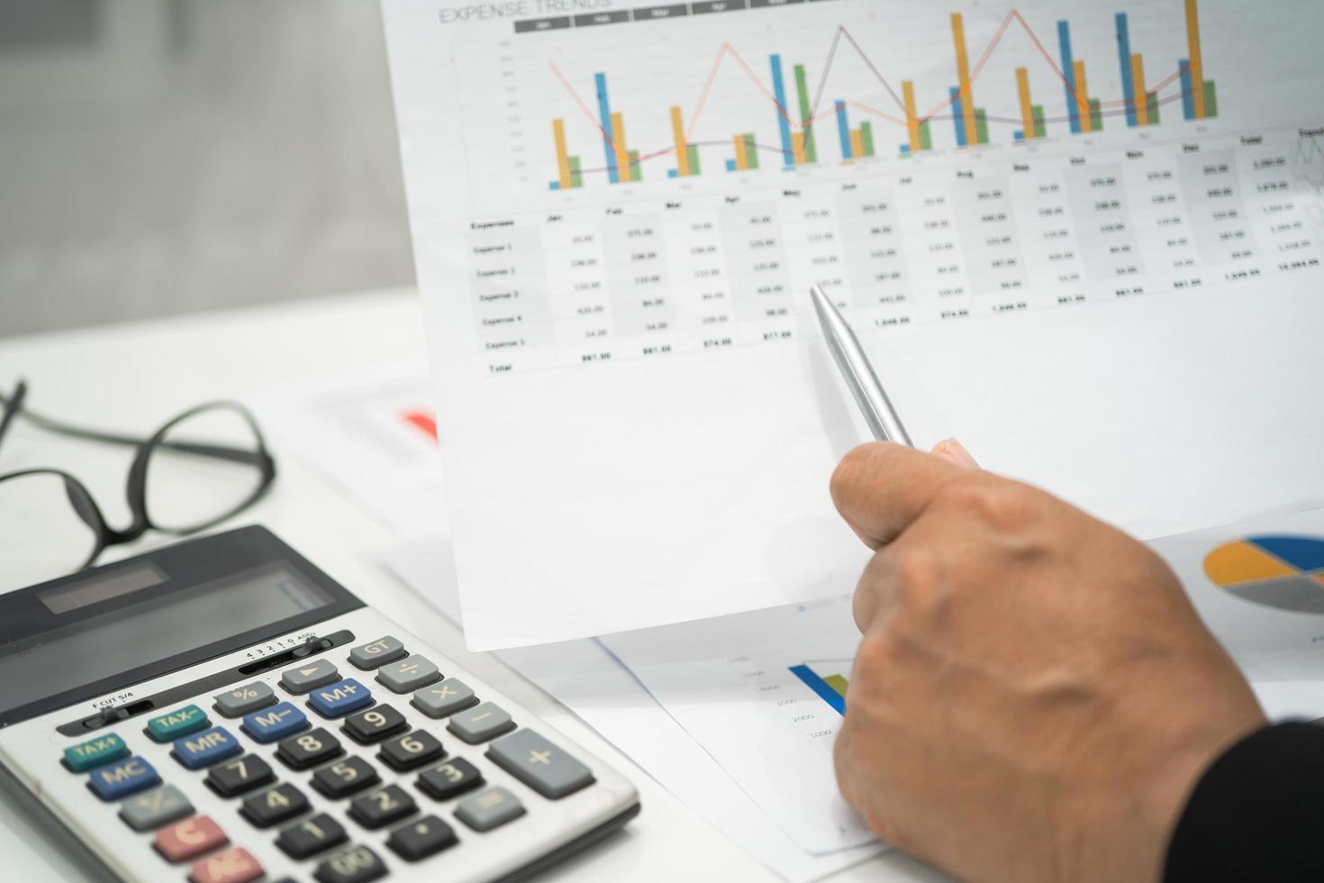 Asian accountant working and analyzing financial reports project accounting with chart graph and calculator in modern office, finance and business concept. photo