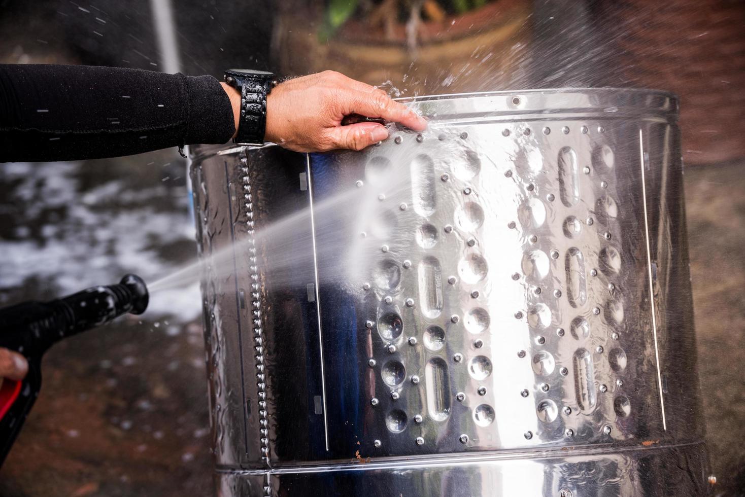 People are using high injection hose pressure wash the stainless steel washing tank until clean. Silver stainless steel washing tank that is being washed by people. photo