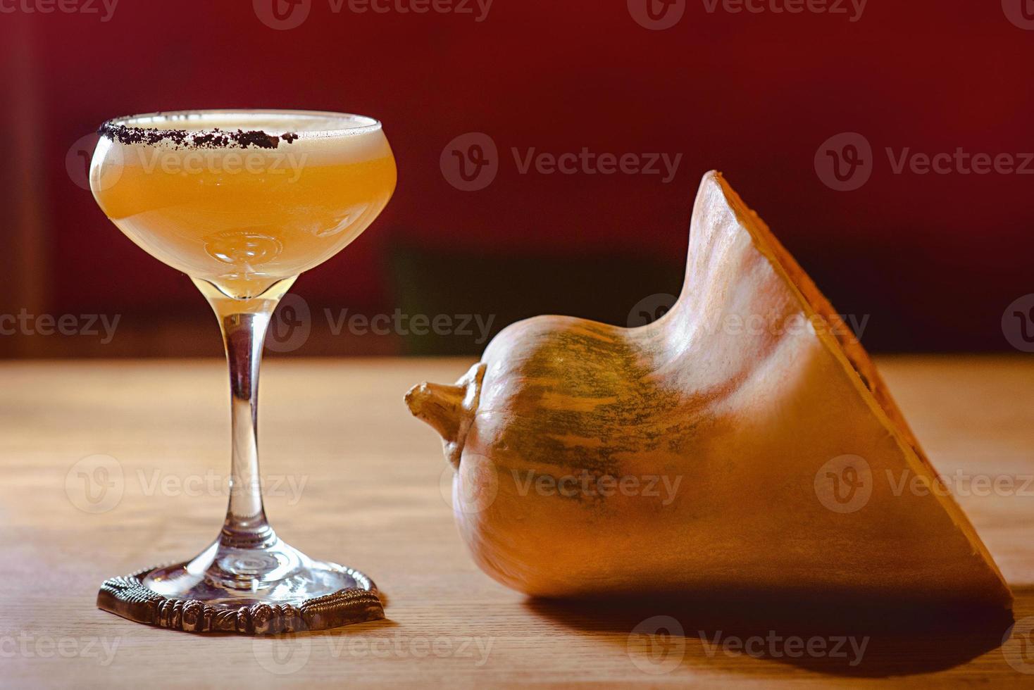 pumpkin alcohol cocktail in a glass and pumpkin on the table photo