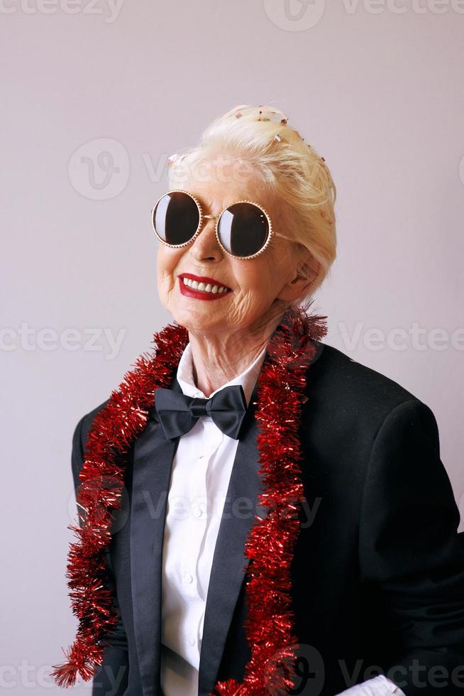Cool senior woman in tuxedo and sunglasses at the party. Fun, party, style, celebration concept photo
