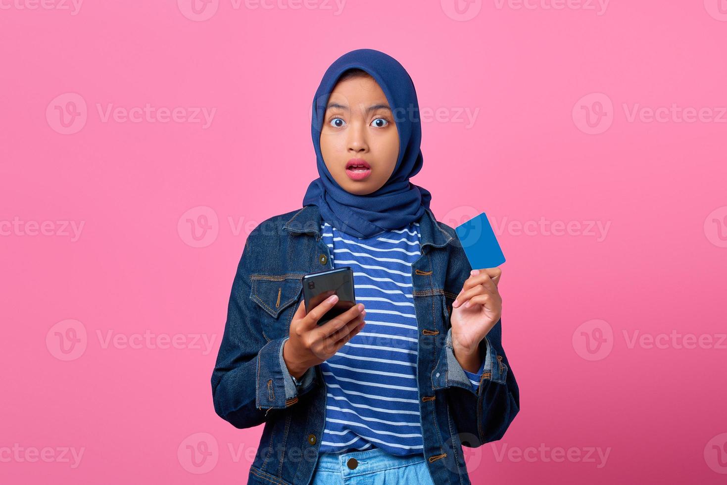 retrato, de, conmocionado, joven, mujer asiática, tenencia, smartphone, mientras, actuación, tarjeta de crédito foto