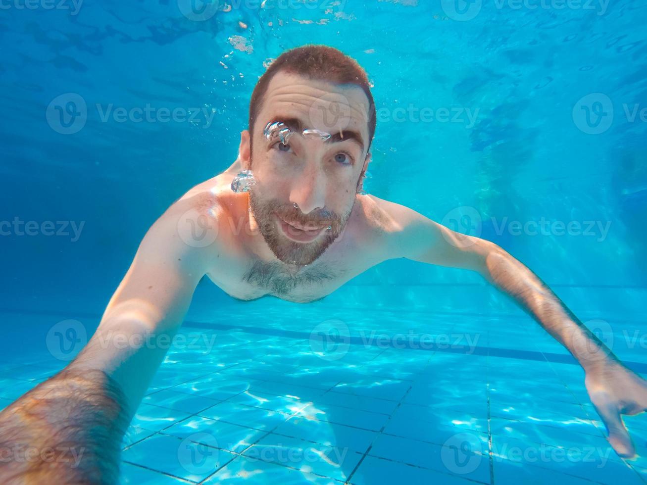 Young handsome man diving underwater in a swimming pool photo