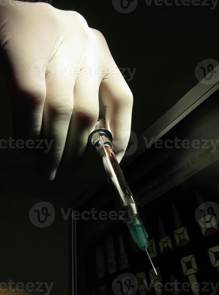 Hand holding dentist syringe to give anesthetic injection, low key photo