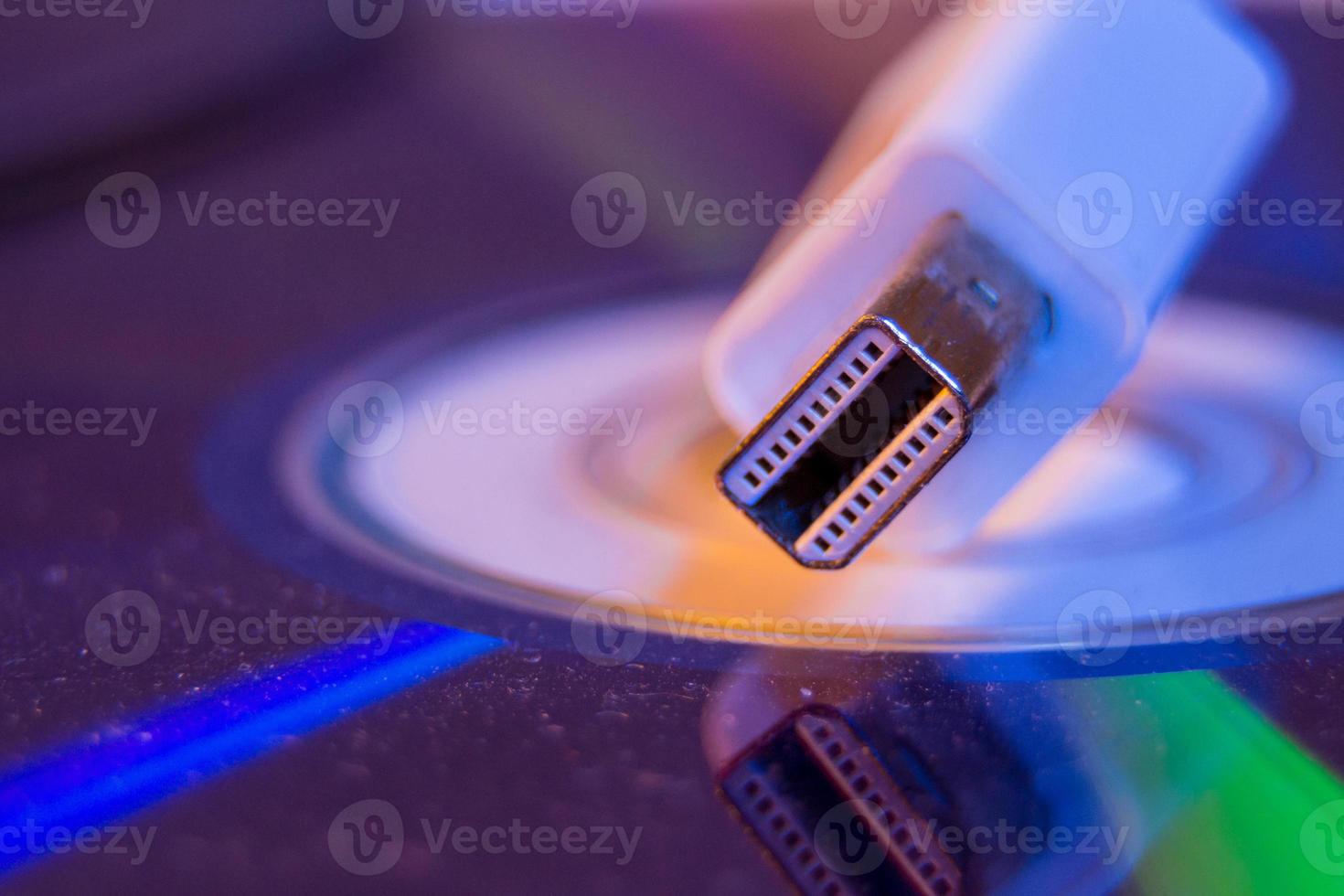 Closeup of white Mini Displayport cable with it's reflection on blank disc photo