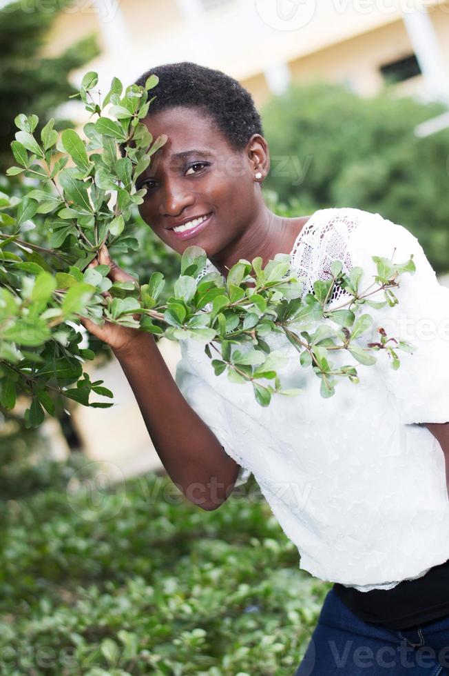 smiling young woman looking through foliage. photo