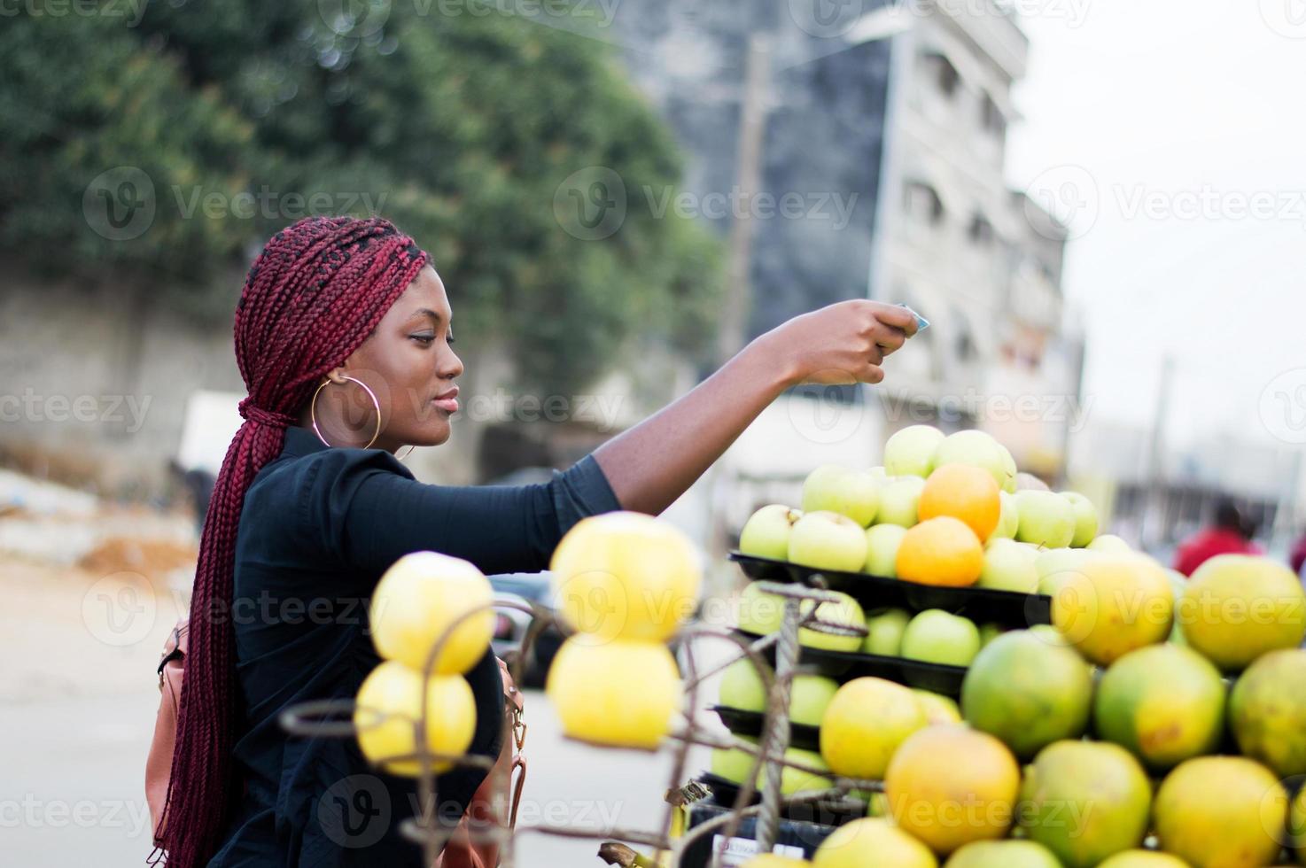 mujer joven pagando frutas en el mercado de la calle. foto