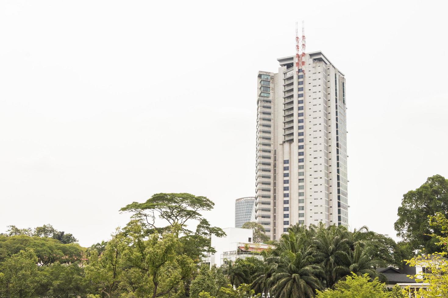 al fondo un alto edificio rascacielos jardines botánicos de Perdana. foto