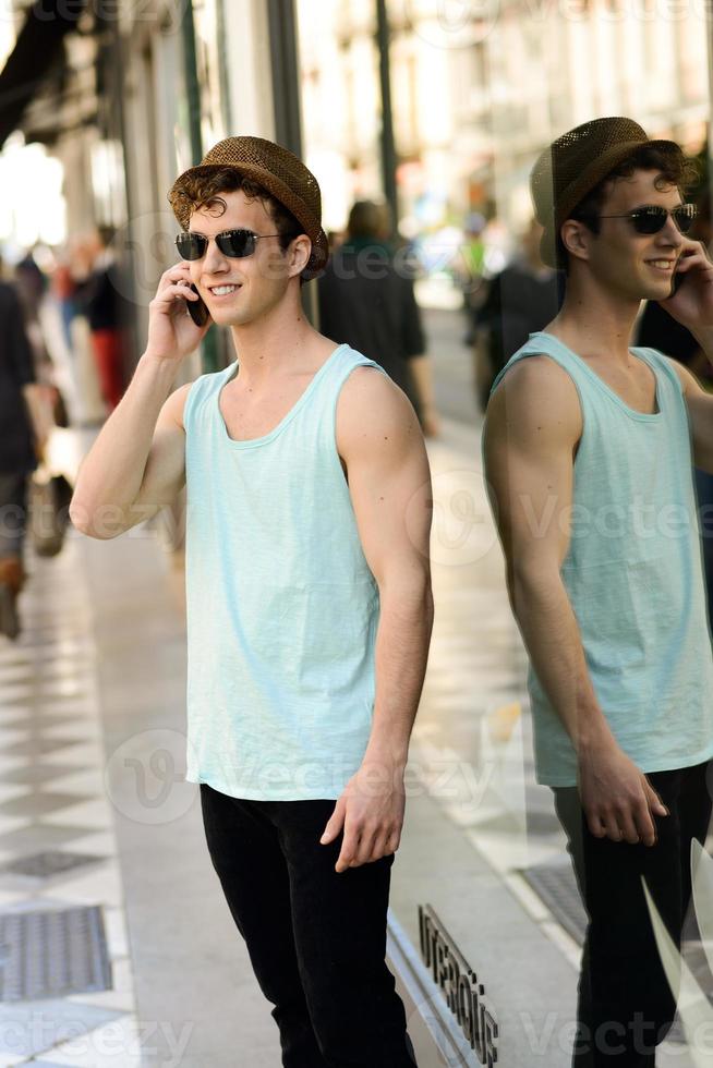 Attractive young man wearing hat talking on the mobile phone photo