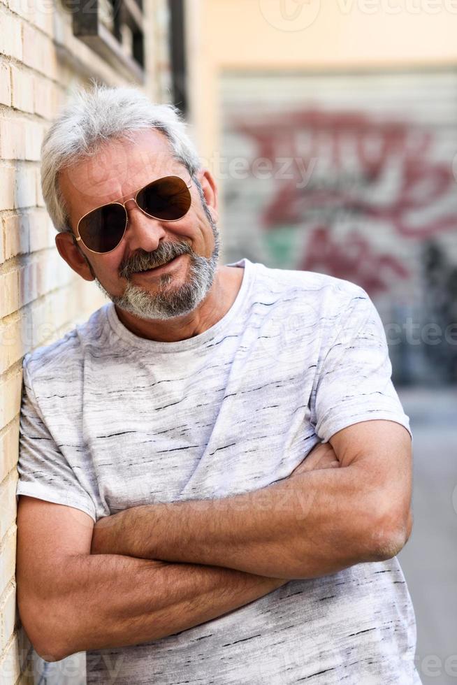 Mature man smiling with aviator sunglasses in urban background photo