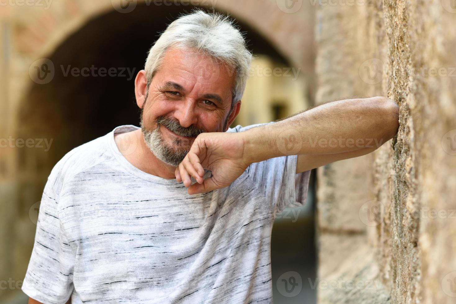 hombre maduro, sonriente, mirar cámara del juez, en, urbano, plano de fondo foto