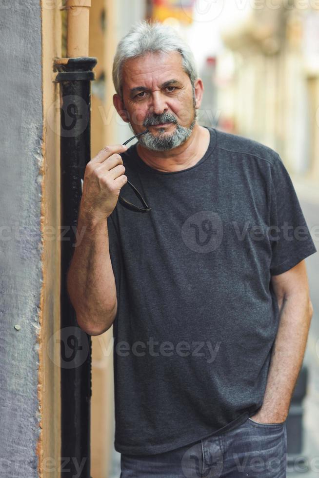 Mature man with grey hair standing in urban background photo