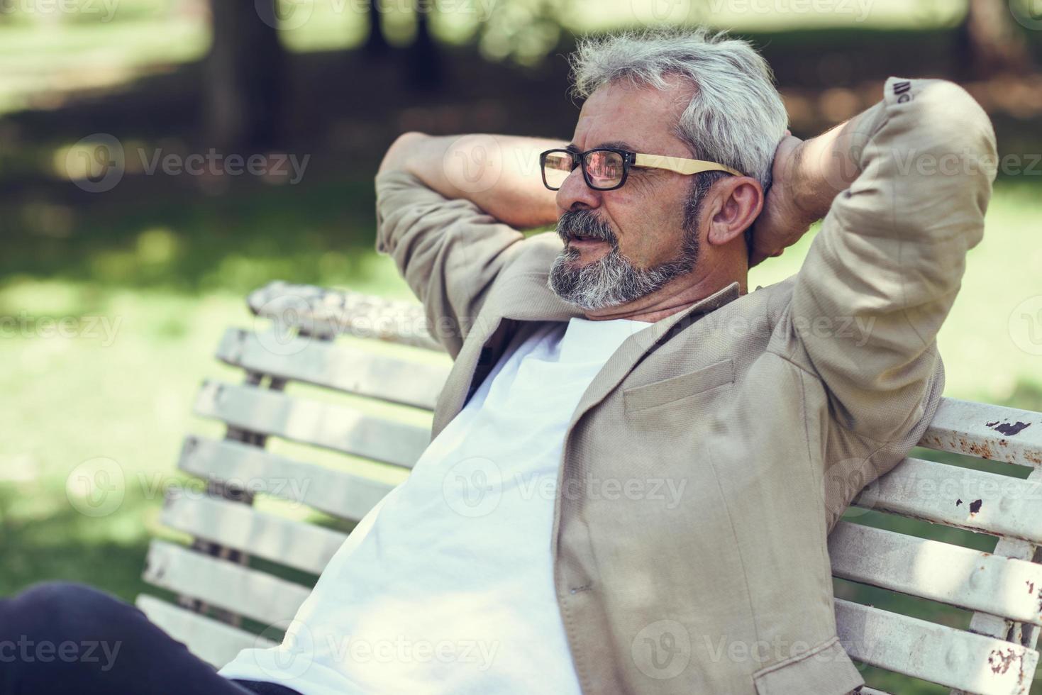 Pensive mature man sitting on bench in an urban park. photo