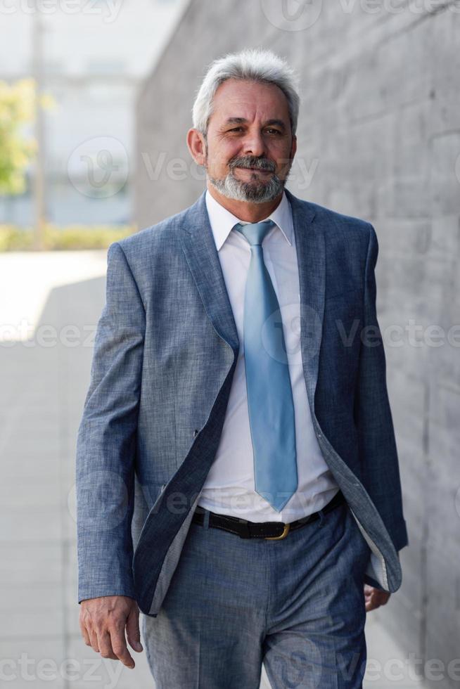 hombre de negocios senior caminando fuera del edificio de oficinas moderno. foto