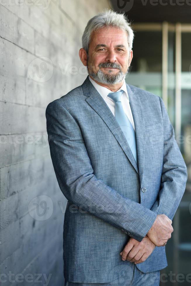 Senior businessman with arms crossed outside of modern office building. photo