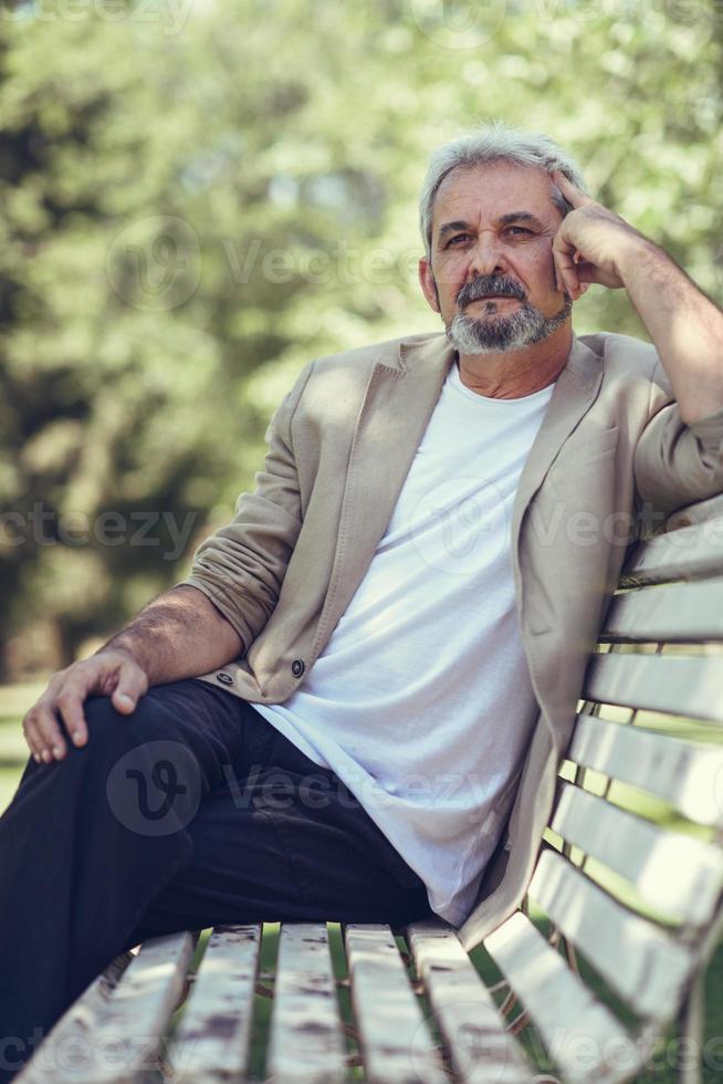 Pensive mature man sitting on bench in an urban park. photo