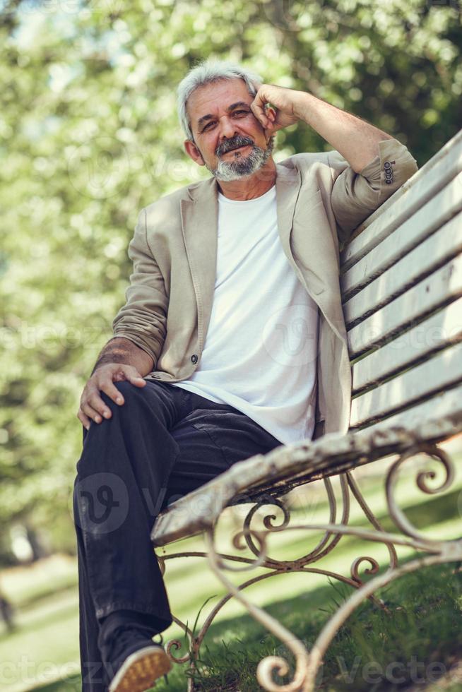 Pensive mature man sitting on bench in an urban park. photo