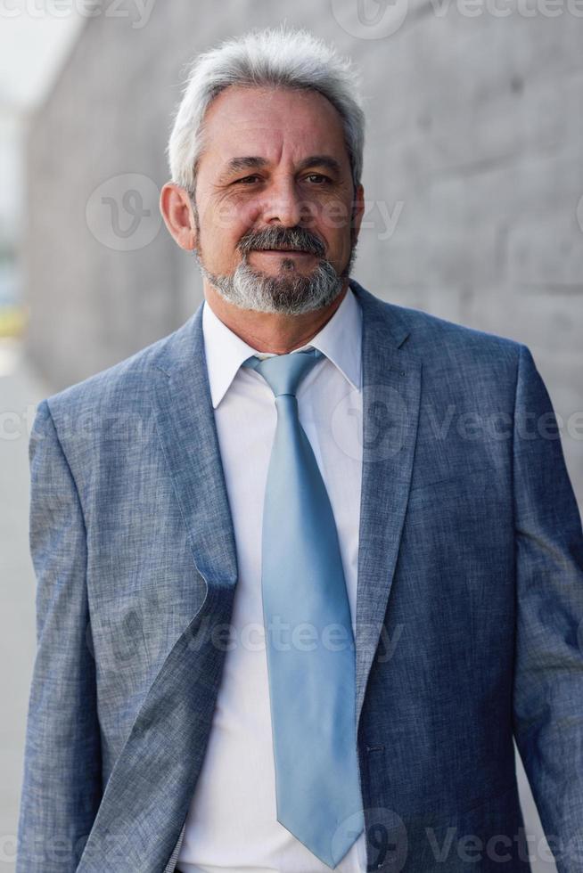 hombre de negocios senior caminando fuera del edificio de oficinas moderno. foto