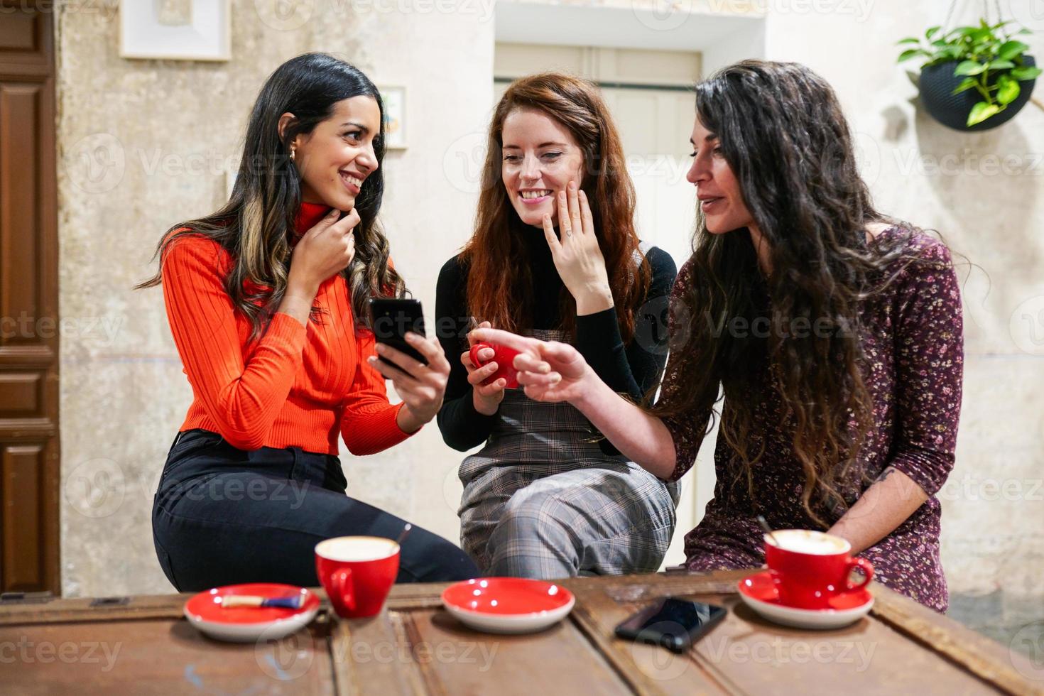 Group of three happy friends drinking coffee in a cafe bar. photo