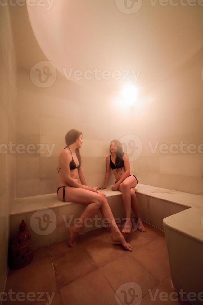 dos mujeres jóvenes disfrutando de hammam o baño turco foto