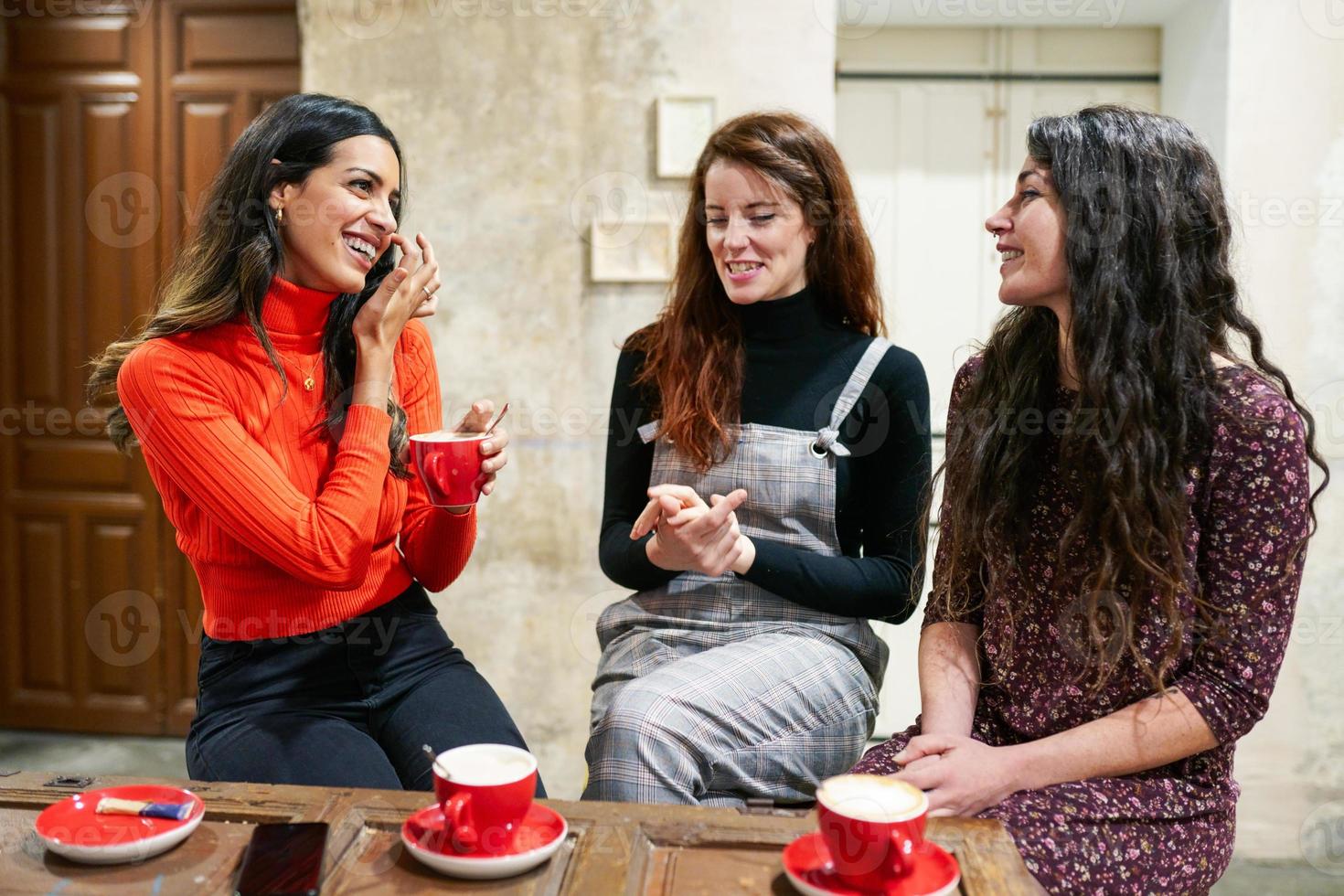 Group of three happy friends drinking coffee in a cafe bar. photo