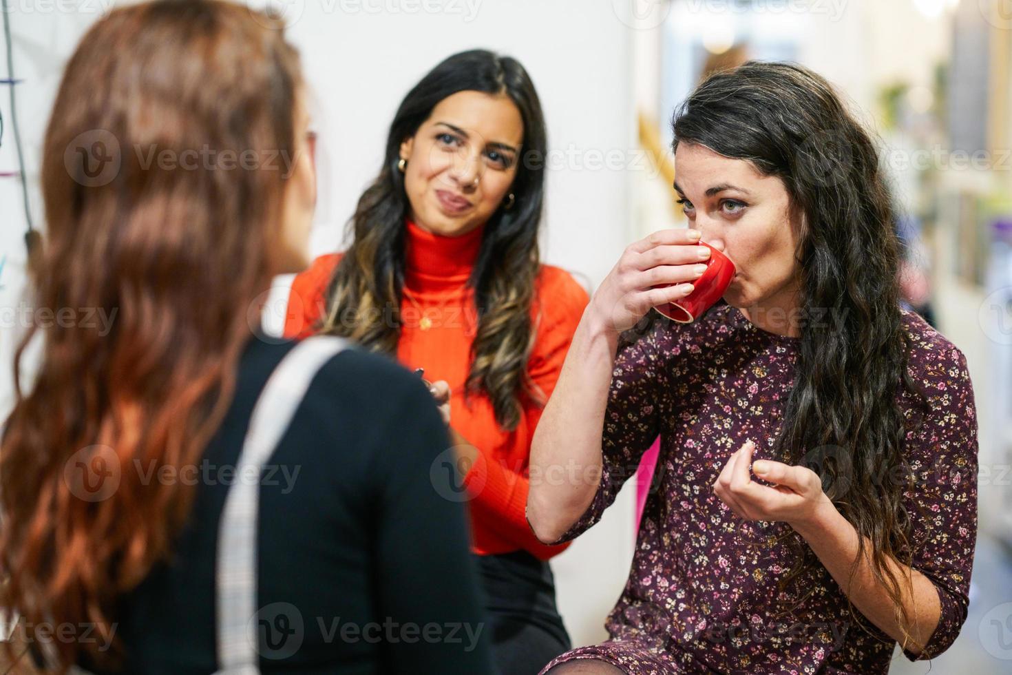 Group of three happy friends drinking coffee in a cafe bar. photo