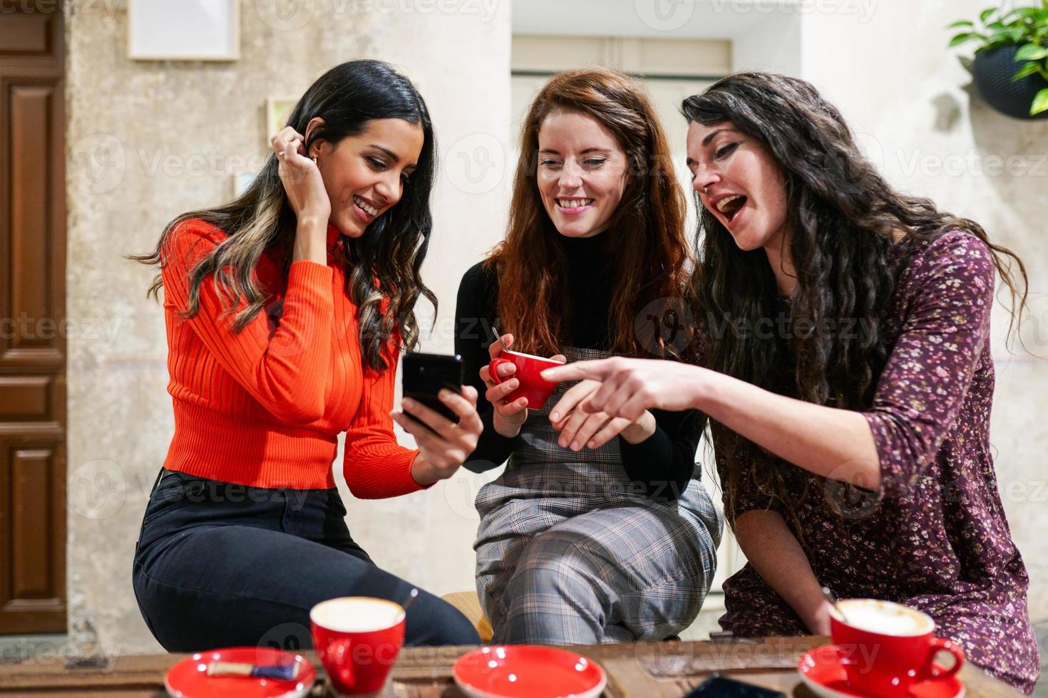 Group of three happy friends drinking coffee in a cafe bar. photo