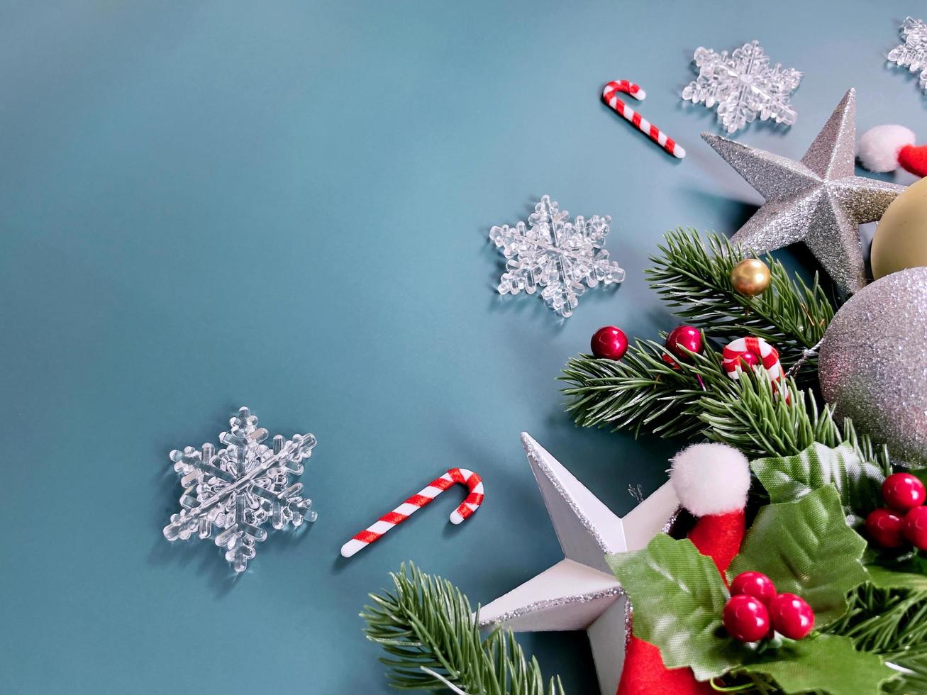 adornos navideños, hojas de pino, bolas de oro, copos de nieve, frutos rojos sobre fondo azul foto