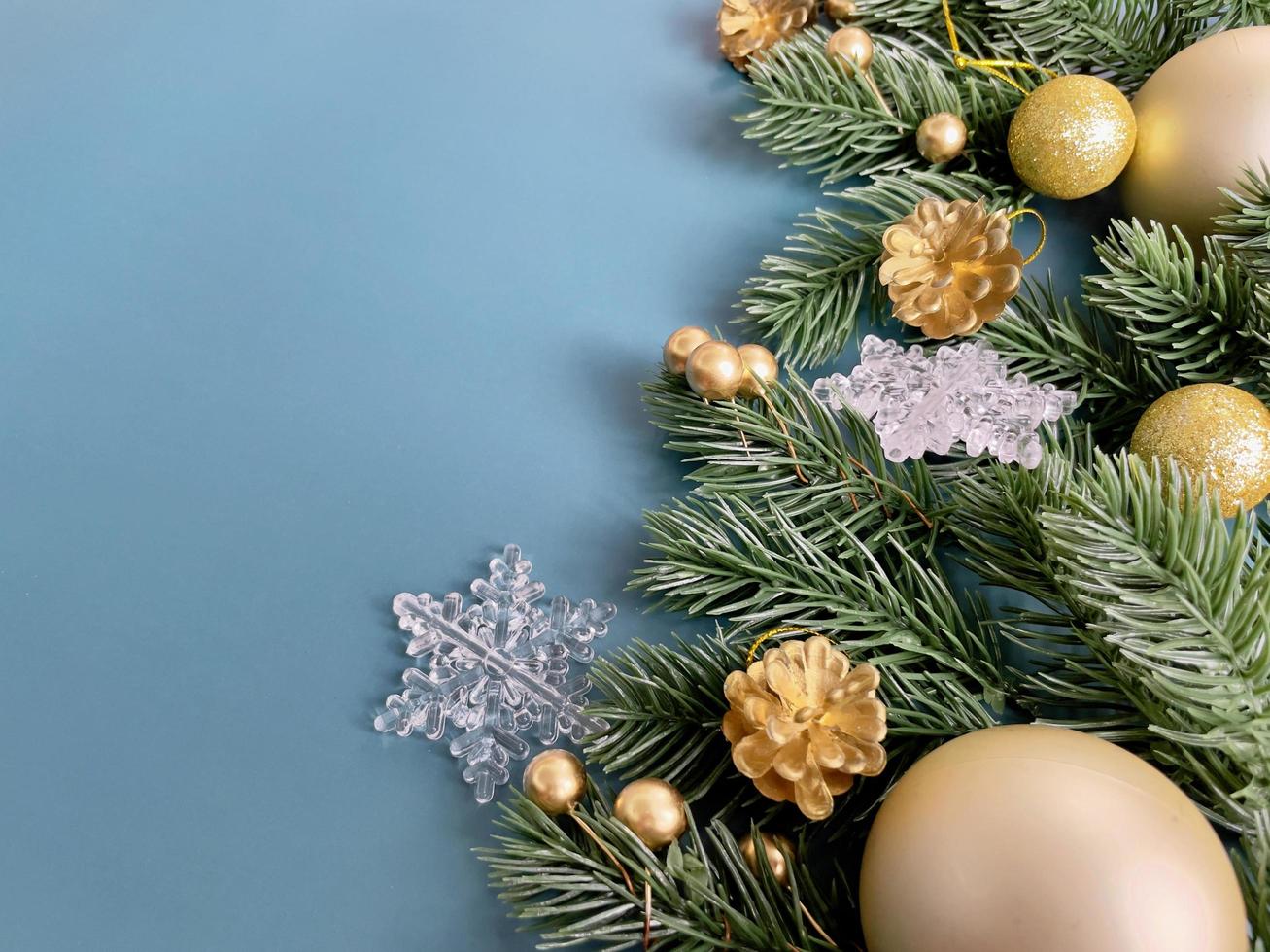 adornos navideños, hojas de pino, bolas doradas, copos de nieve, bayas doradas sobre fondo azul foto