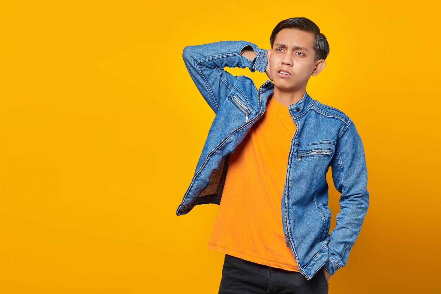 Portrait of confused asian man looking sideways on yellow background photo