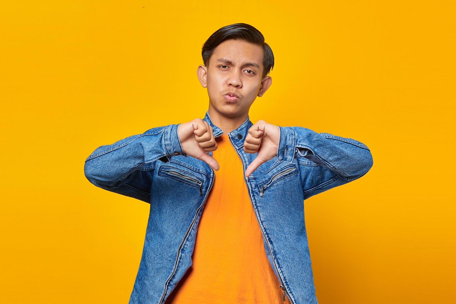 young asian man looking unhappy ang anry showing rejection with thumbs down gesture photo