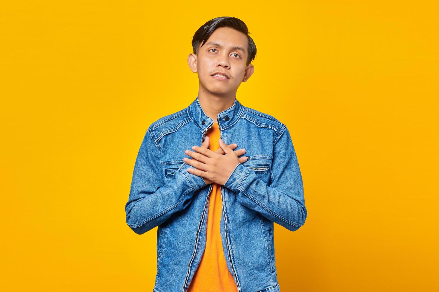 Retrato de joven asiático sorprendido con las manos en el pecho y mirando hacia el lado foto