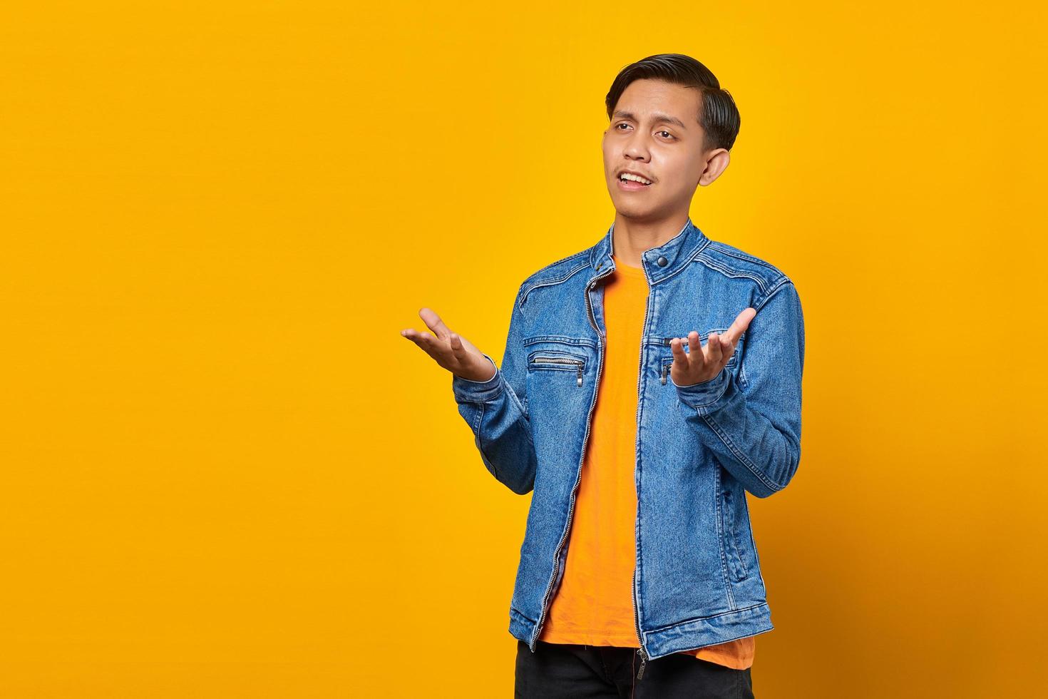 Portrait of asian man surprised with confused and displeased expression on yellow background photo