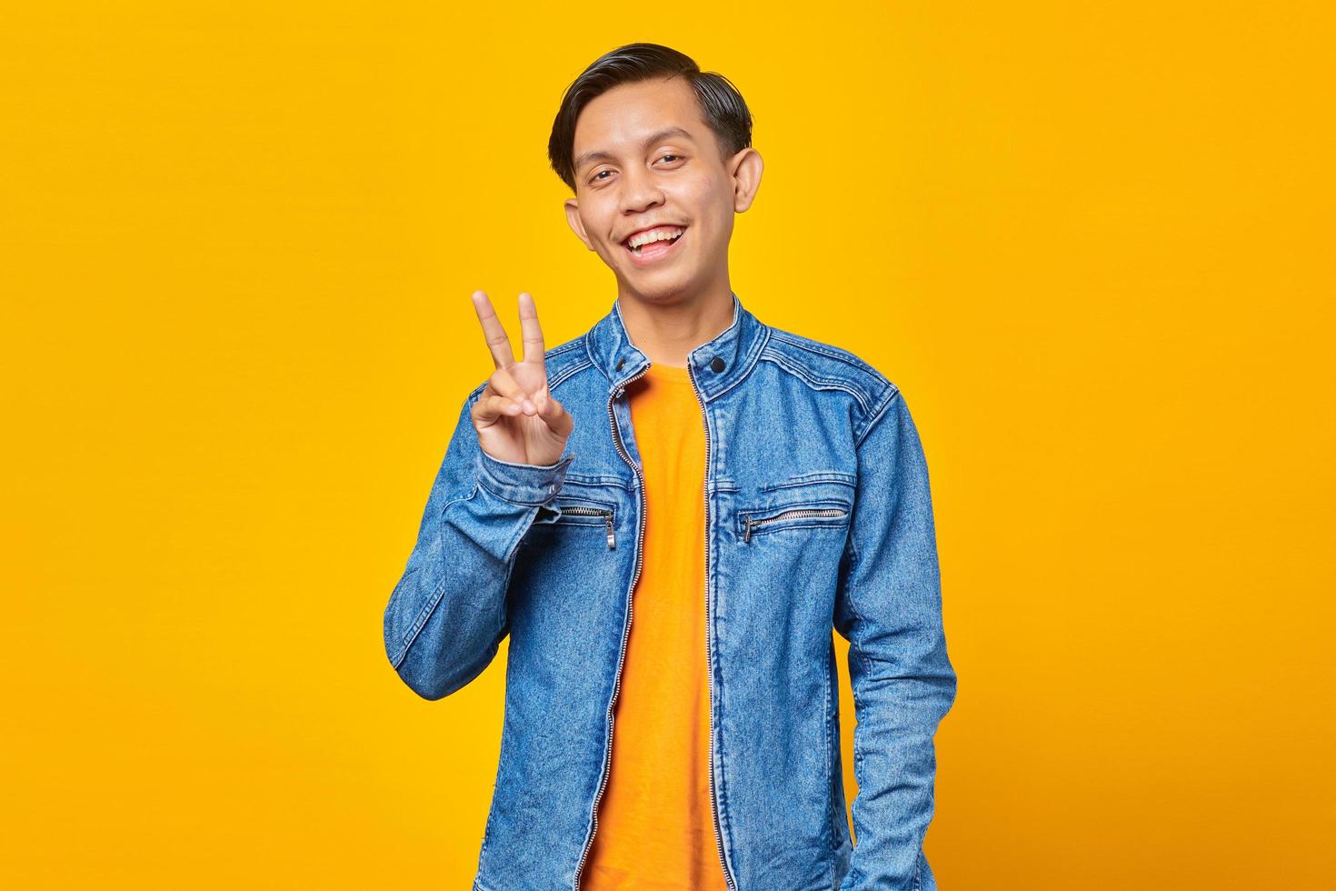 Attractive smiling young Asian man doing peace sign with hand photo