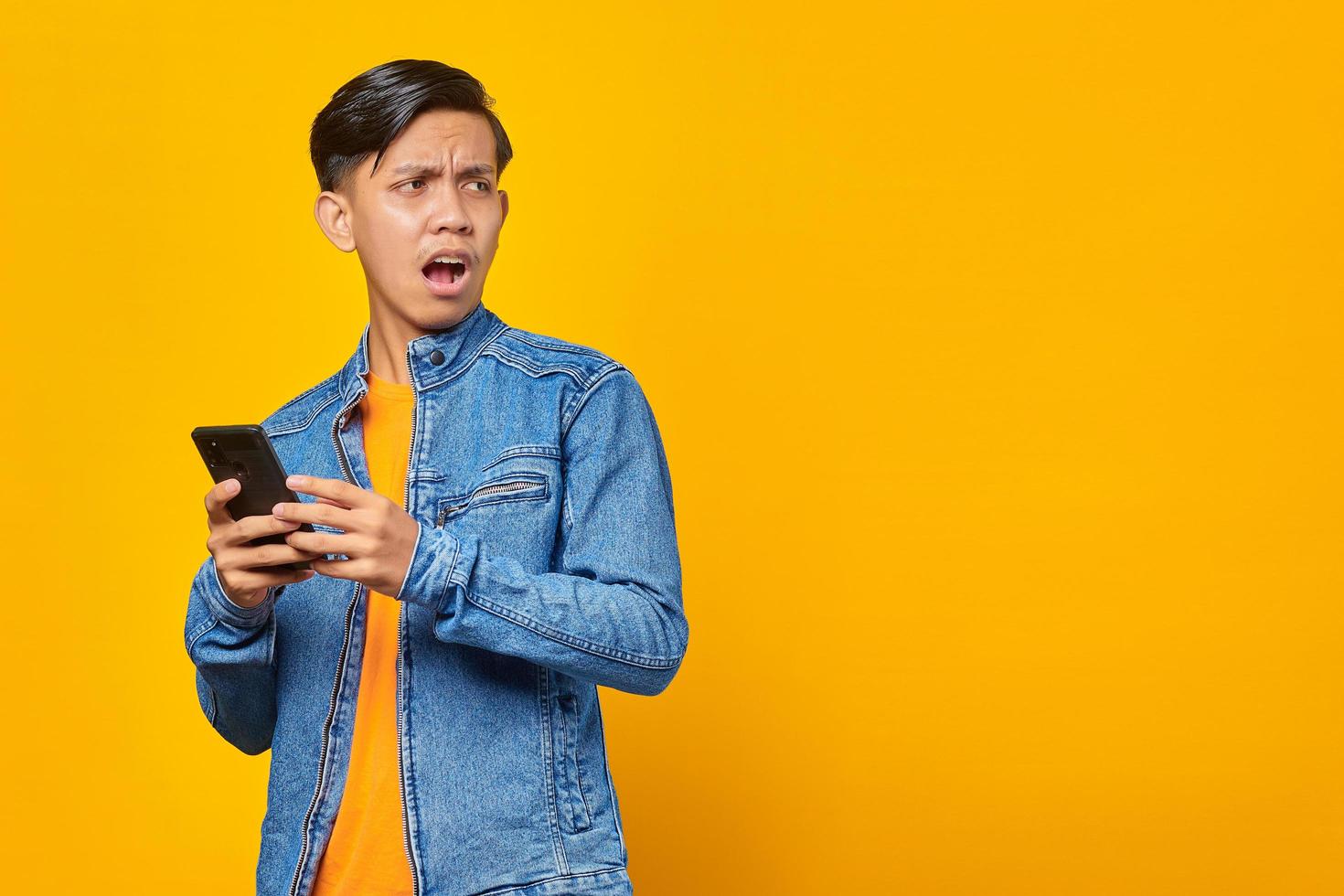 Conmocionado joven asiático mirando el mensaje en el teléfono inteligente foto