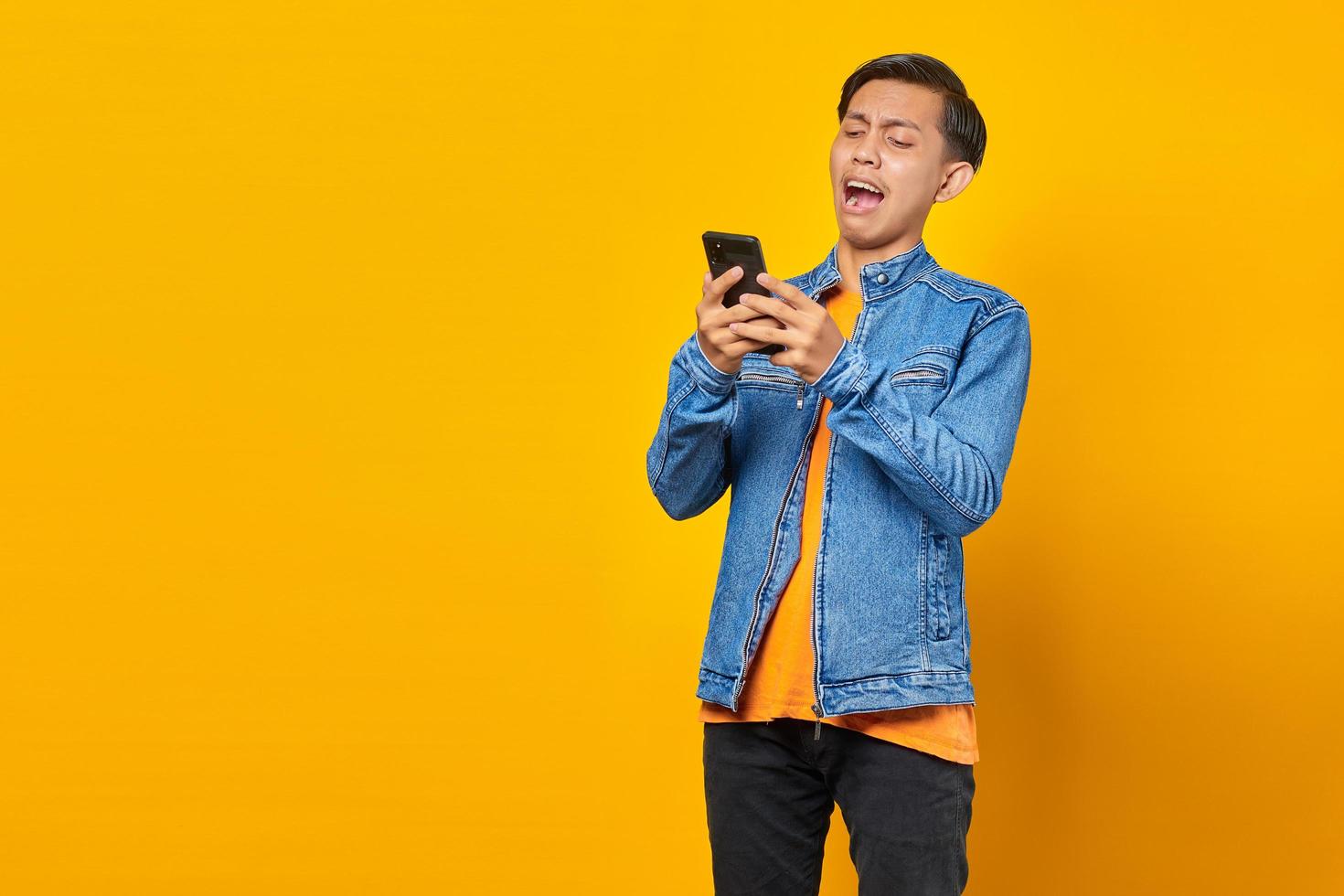 Conmocionado joven asiático mirando el mensaje en el teléfono inteligente foto