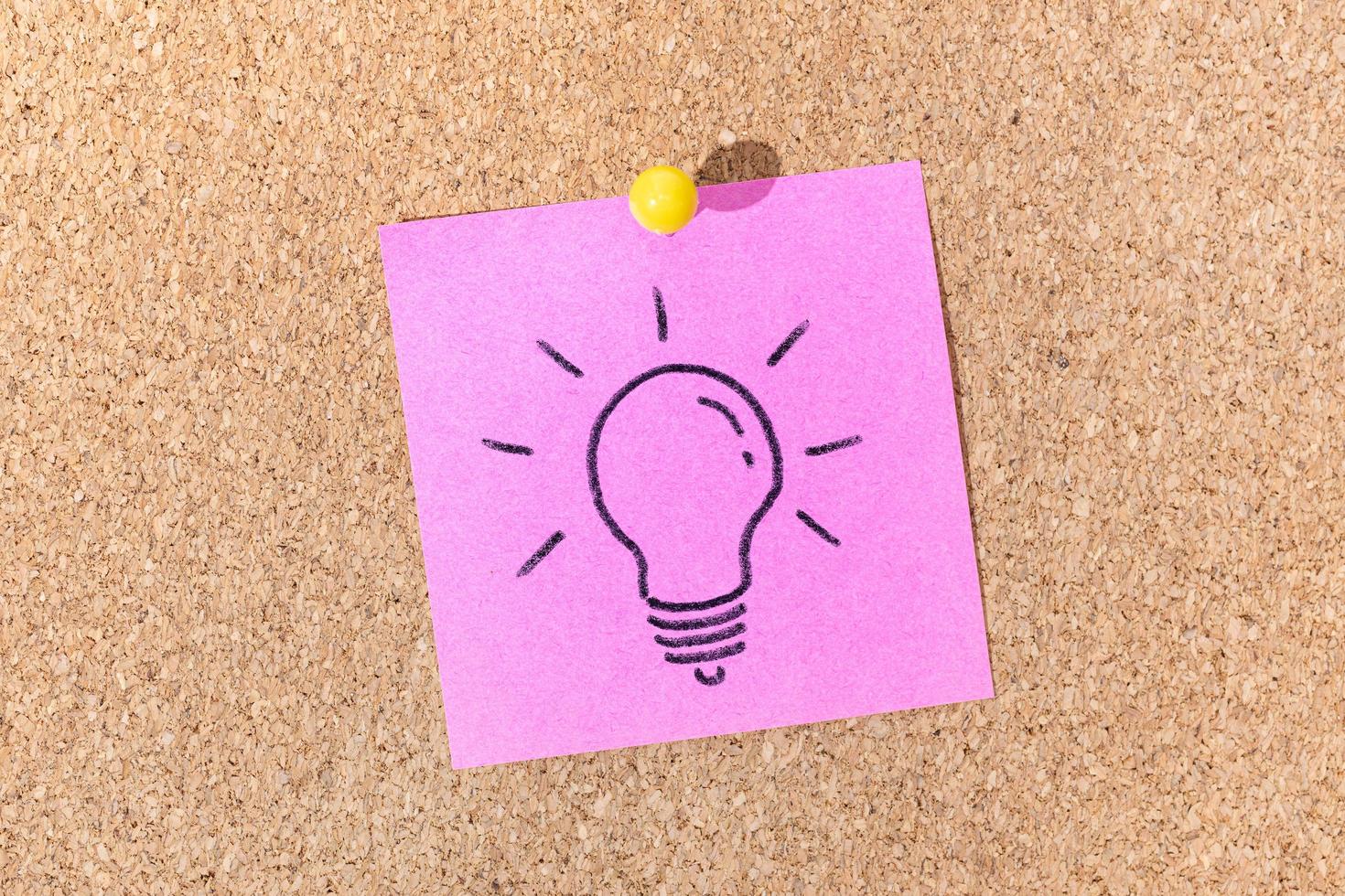 Bright Idea or Creative process concept. Light bulb drawing on sticky note on cork board photo